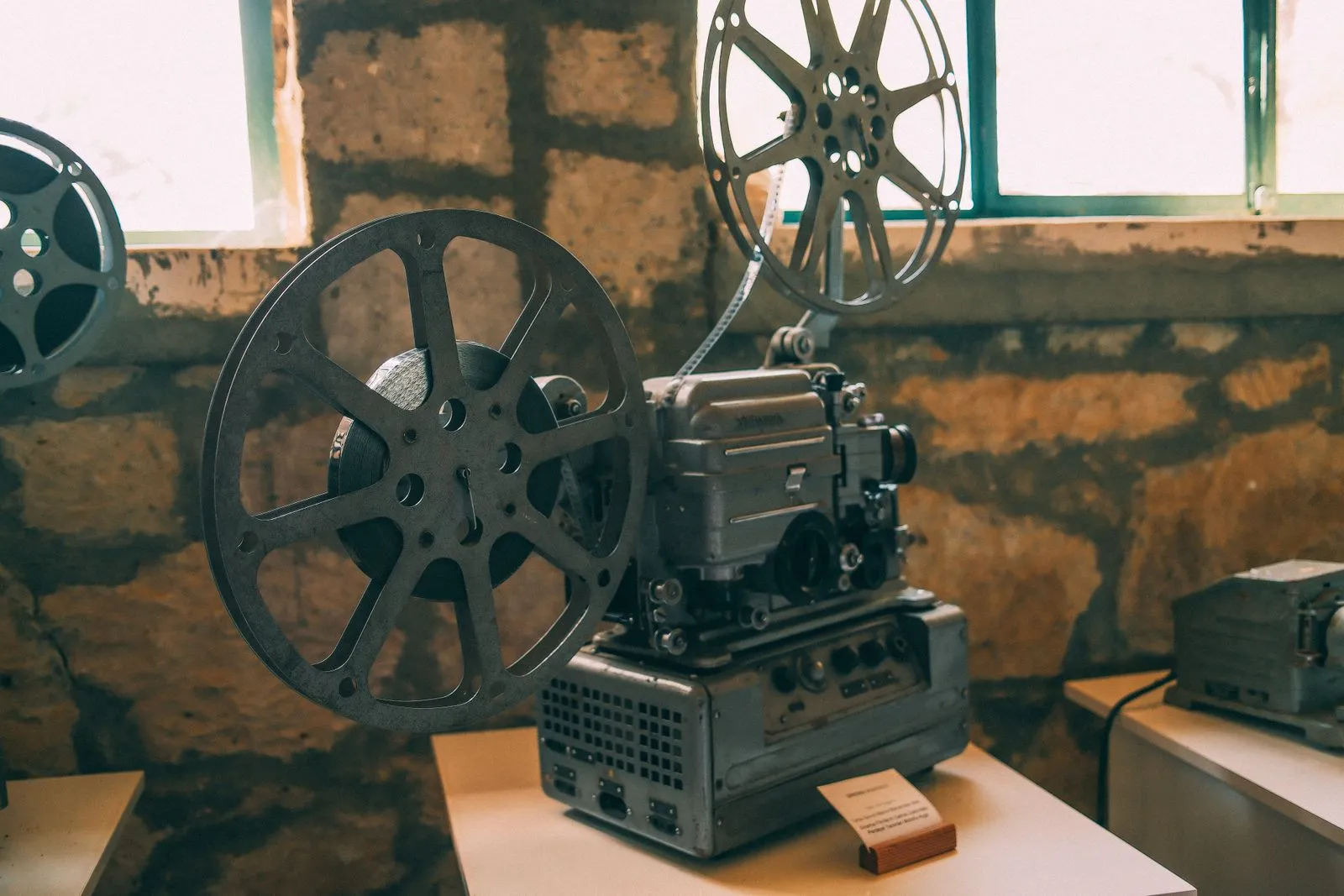 A vintage film projector in a dim room, evoking classic movie-theater projection from the 90s and 2000s film era